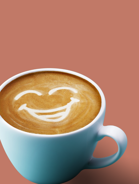 tasse de café sur fond marron avec motif de visage souriant dessiné dans la mousse du café